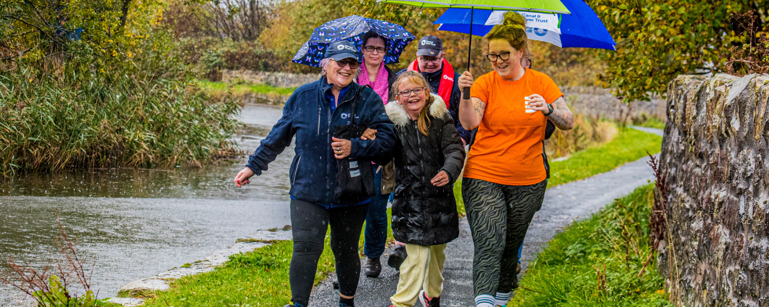 a group of people walk along the canal they are smiling